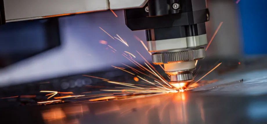 Close-up of a CNC laser cutting or welding head processing a metal sheet