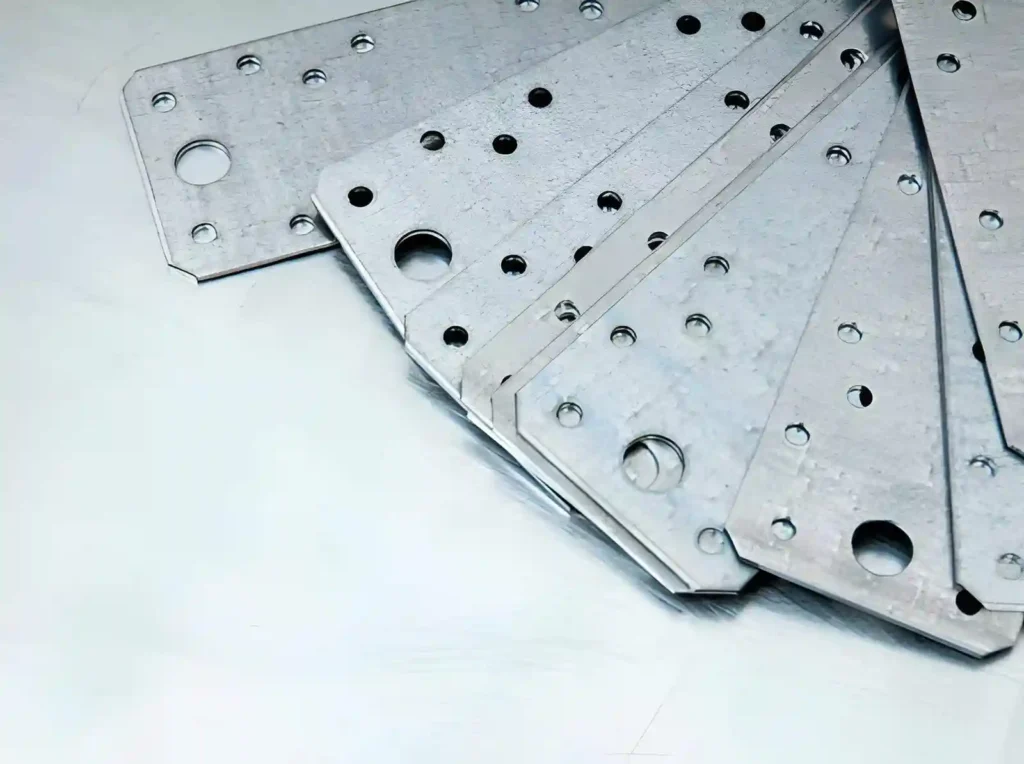 The image shows sheet-metal blanked parts with uniform cut shapes, prepared for further processing.