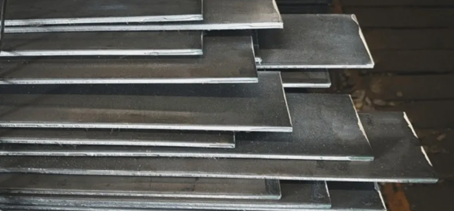 Close-up view of stacked rectangular hot-rolled steel plates with a textured finish
