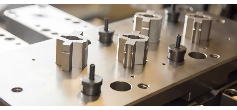 Multiple precision-machined metal blanking punches and guiding pins positioned on an industrial die plate block