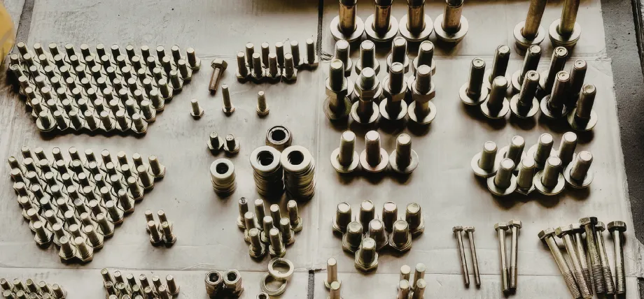 Various sizes and types of industrial bolts, nuts, and washers organized on a flat surface.