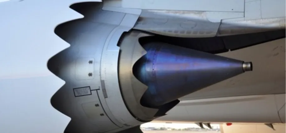 Close-up of a jet engine exhaust nozzle featuring chevron-edged cowlings and a heat-treated blue metal cone.