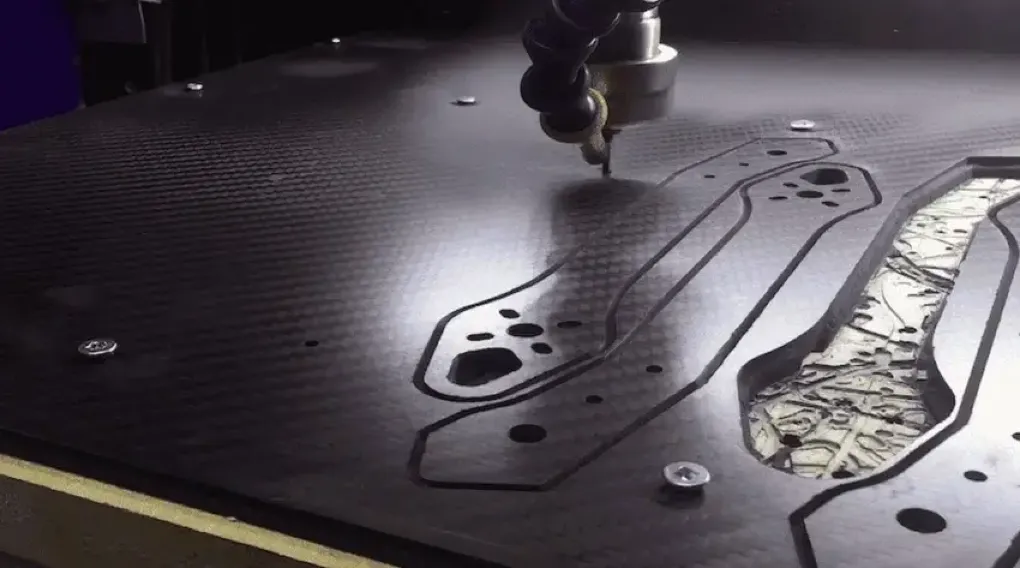 CNC router cutting complex part profiles into a carbon fiber sheet with optimized toolpaths