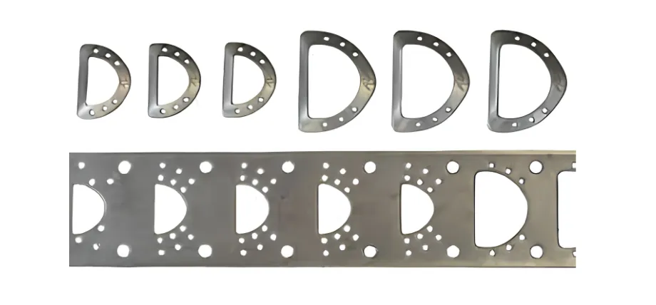 A metal strip showcasing successive stages of a progressive stamping sequence alongside the finalized D-shaped components.