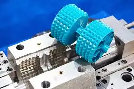 Close-up of two blue textured rollers mounted inside a metal mold or machining fixture.
