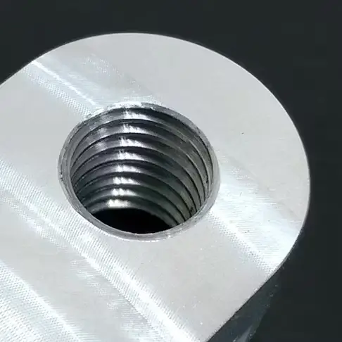 Close-up of a metal part with a cleanly machined internal threaded hole.