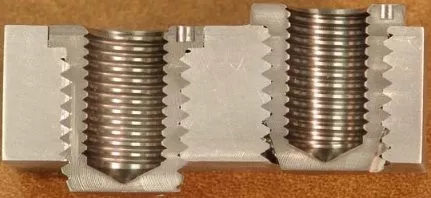 Cross-sectional metal block showing detailed internal screw threads and cut profile.
