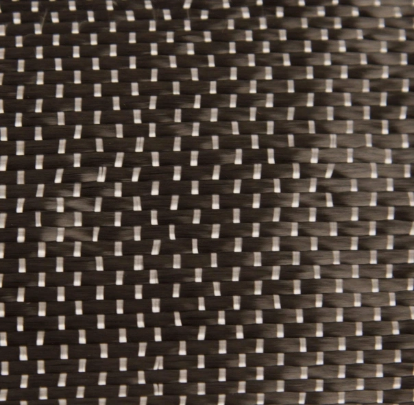 Close-up of unidirectional carbon fiber fabric with parallel fibers and white grains