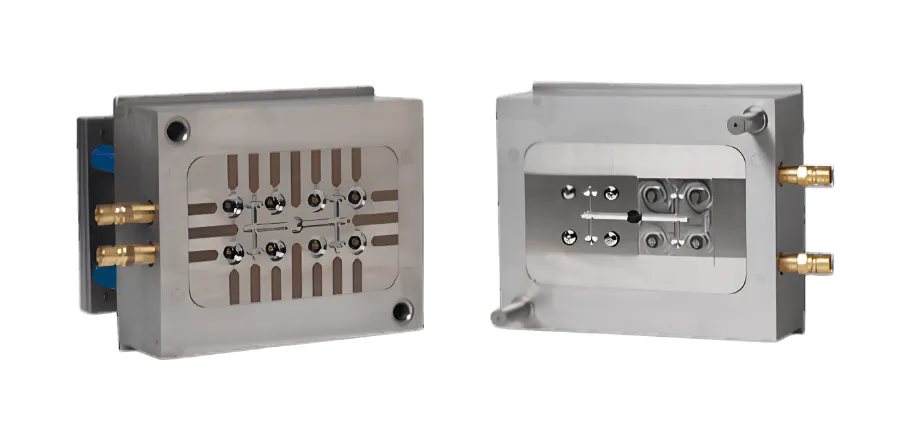 A two-part metal injection mold core and cavity block showing multiple matching geometric slots, runners, and brass water line connectors.