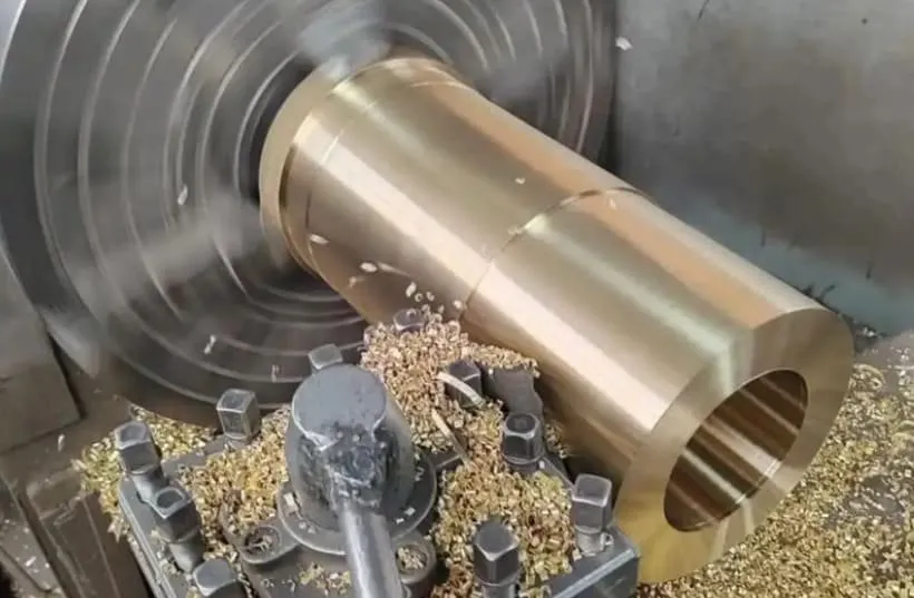 large bronze cylinder along with chips flying during CNC operations