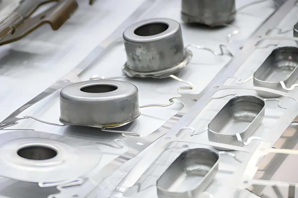 The image depicts deep-drawn stamped metal parts produced by forming flat sheet metal into shaped components through a stamping-and-drawing process. 