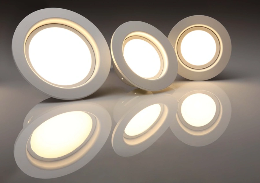 Three polycarbonate-lens LED round panel lights of varying sizes with a warm white glow on a reflective surface.