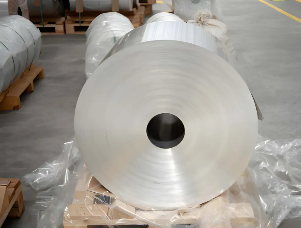 The image shows a large aluminium roll at the factory setting.