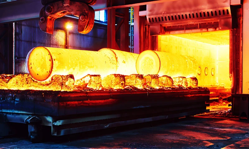 Large steel cylinders are being heated in an industrial heat treatment furnace.