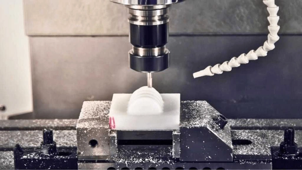 A close-up view of Machining glass-filled nylon in a milling machine; an end mill tool removing materials from the workpiece