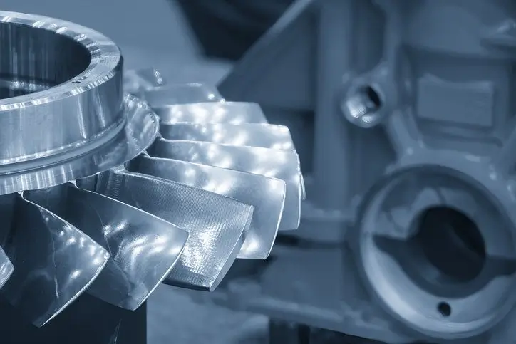 Close-up of a shiny machined metal turbine part with detailed blades.