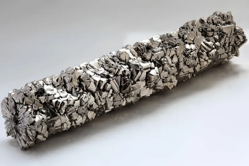 Raw titanium metal ingot displaying characteristic crystal grain structure, used in lightweight alloy applications