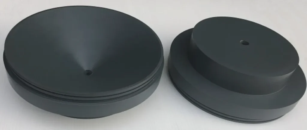 Two dark grey PVC discs with concave faces and center-drilled holes, in different sizes, produced through machining of Rigid PVC