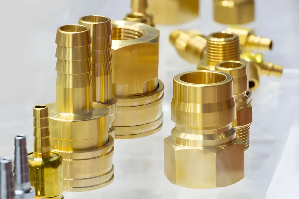The image shows a close-up of machined brass pipe connector parts used in the mold and die industry.
