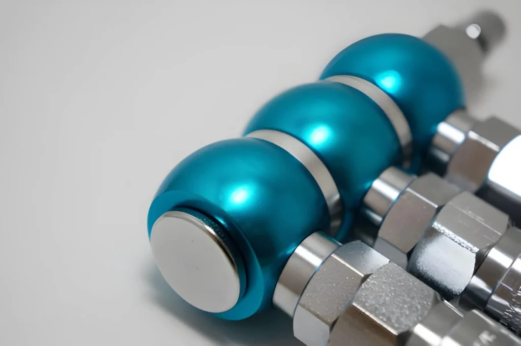 The image shows high-precision aluminum CNC-machined parts arranged on a surface. The parts have cylindrical shapes with smooth finishes, threads, and stepped features.