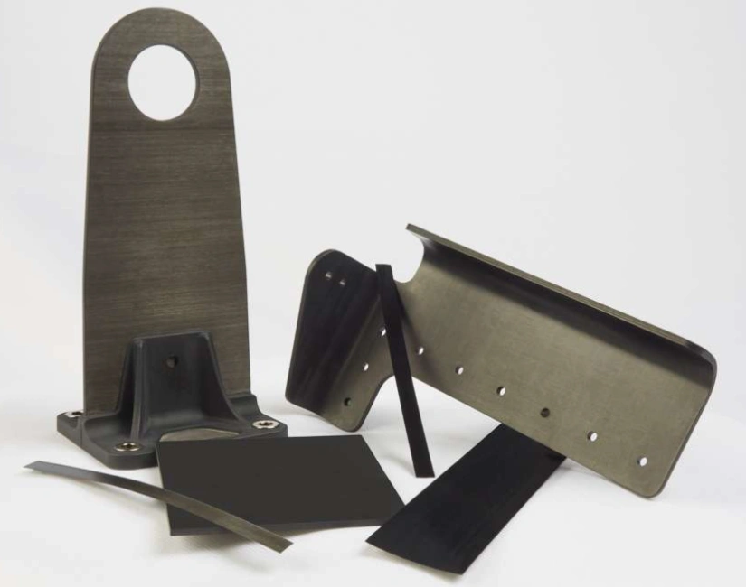 Carbon-filled PEEK aerospace structural brackets and flat panels on a white background