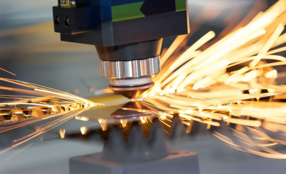 Close-up of a laser cutting head generating intense sparks while cutting a brass sheet, illustrating high reflectivity during the process.  