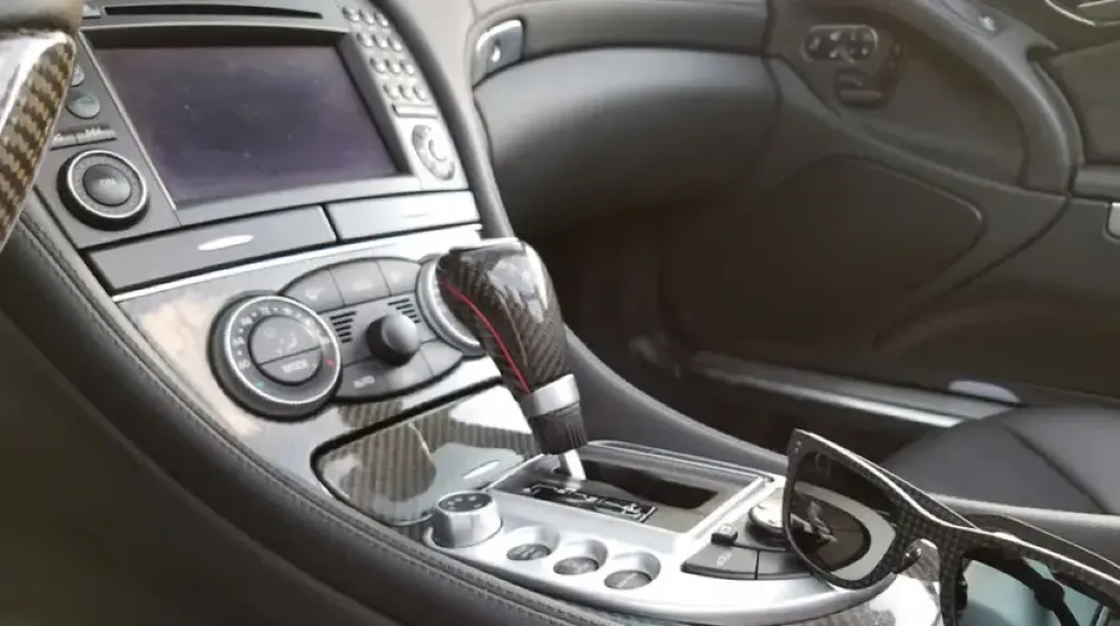 Car interior center console with woven carbon fiber trim panels, gear shift knob, and door panel inserts.