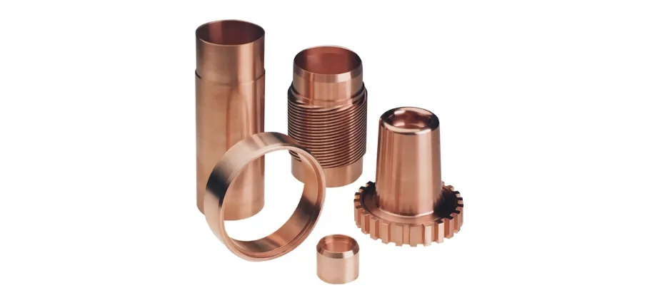 Several cylindrical and conical copper parts with varied diameters and threaded sections against a clean white background.