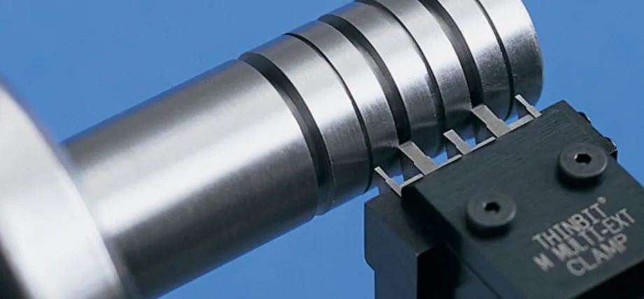 A Thinbit multi-clamp tool holder utilizing four parallel inserts to cut simultaneous grooves into a steel shaft.