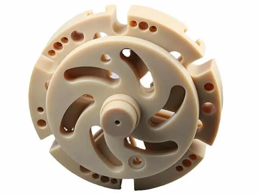 Machined food-grade PEEK rotor disc with curved slots and mounting holes on a white background
