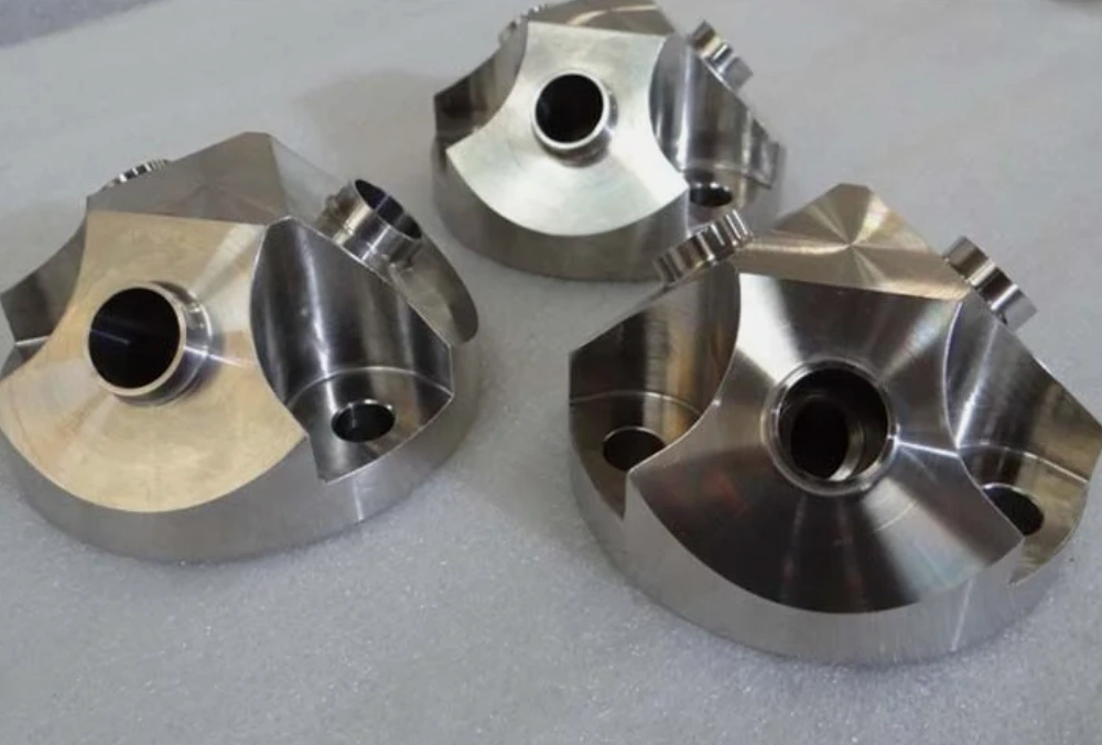 Three precision-machined Inconel components with bored holes and contoured faces showing characteristic nickel-alloy surface finish
