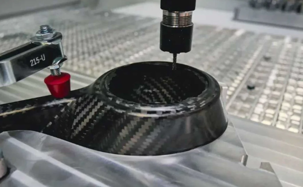 CNC spindle drilling into a curved woven carbon fiber drone motor mount nacelle