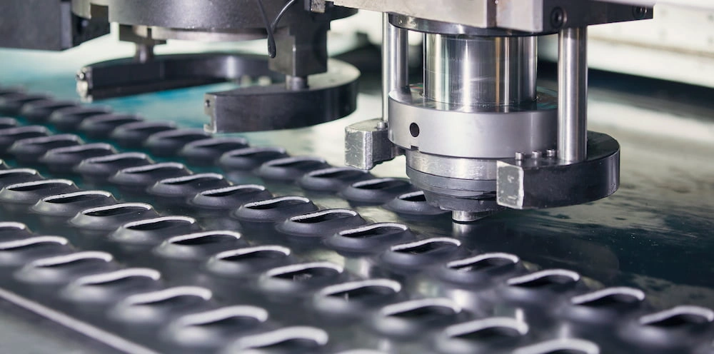 CNC turret punch press creating louvered holes in dark metal sheet