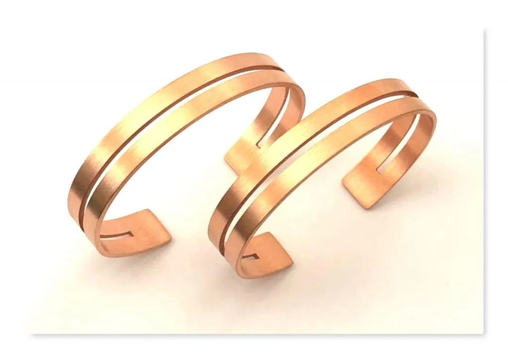 Two polished antimicrobial copper cuff bracelets with laser-cut center slit on white background