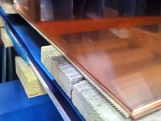 Stacked copper C103 alloy sheets on warehouse shelving with protective paper interleaving