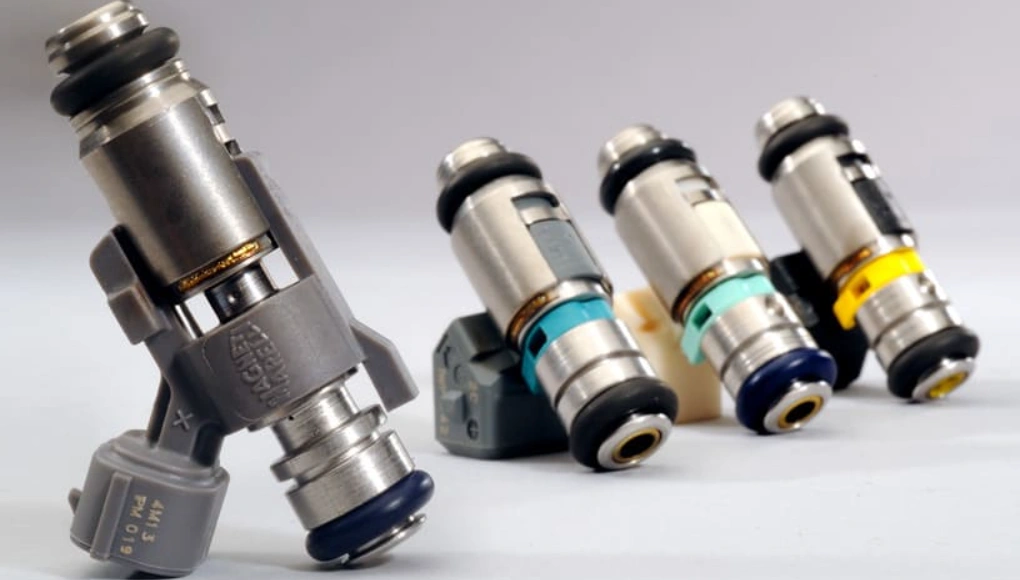 Four automotive fuel injectors with micro-machined nozzle tips arranged on white background