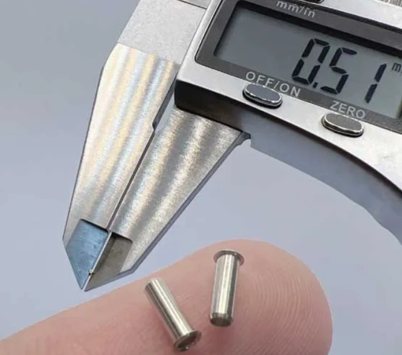 Digital caliper measuring tiny micro-machined stainless steel pins on fingertip, 0.51mm