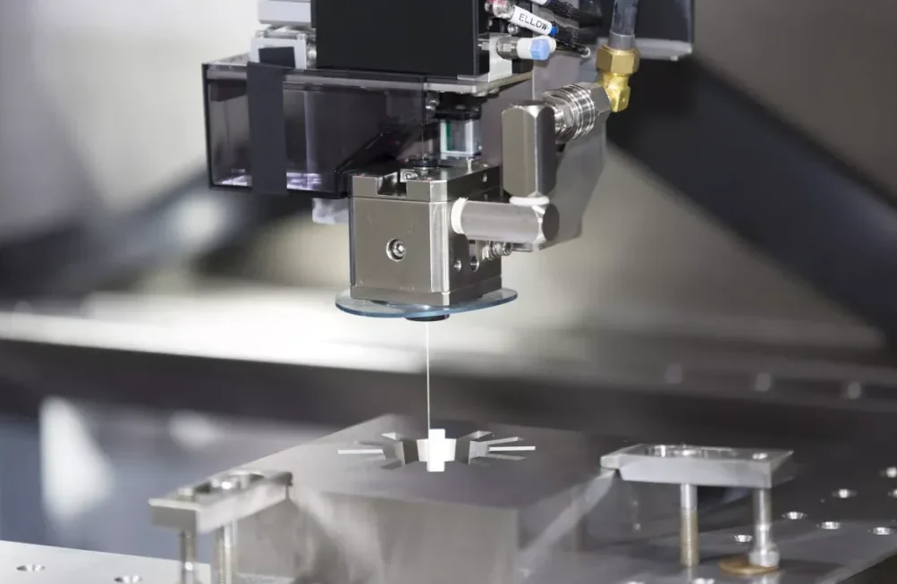 Wire EDM machine cutting a precise steel part clamped to the worktable