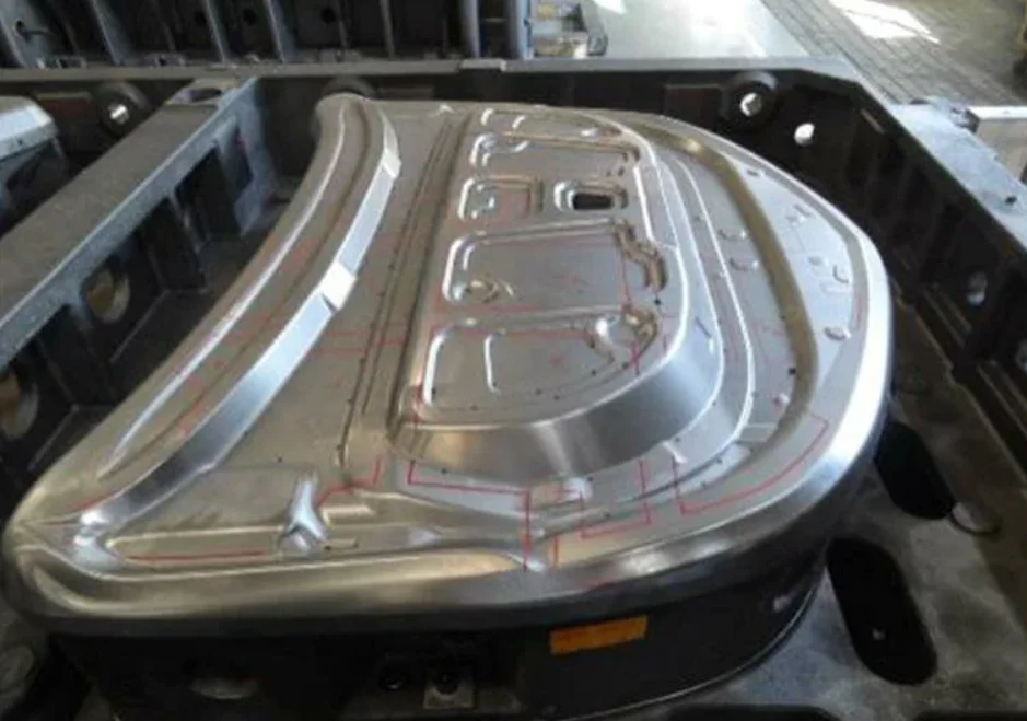 Large hardened steel automotive stamping mold with contoured surface and marked tooling lines